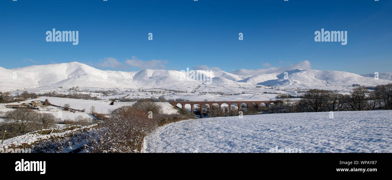 The disused Firbank viaduct with the Howgill Fells in the background, covered in snow. Cumbria, UK. Stock Photo