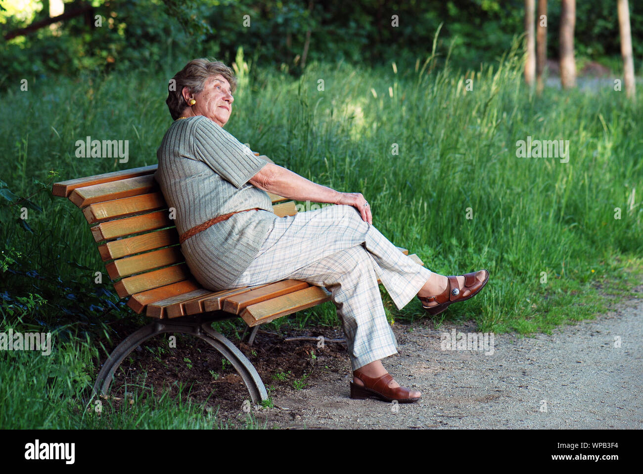 elderly woman sitting on park bench Stock Photo - Alamy