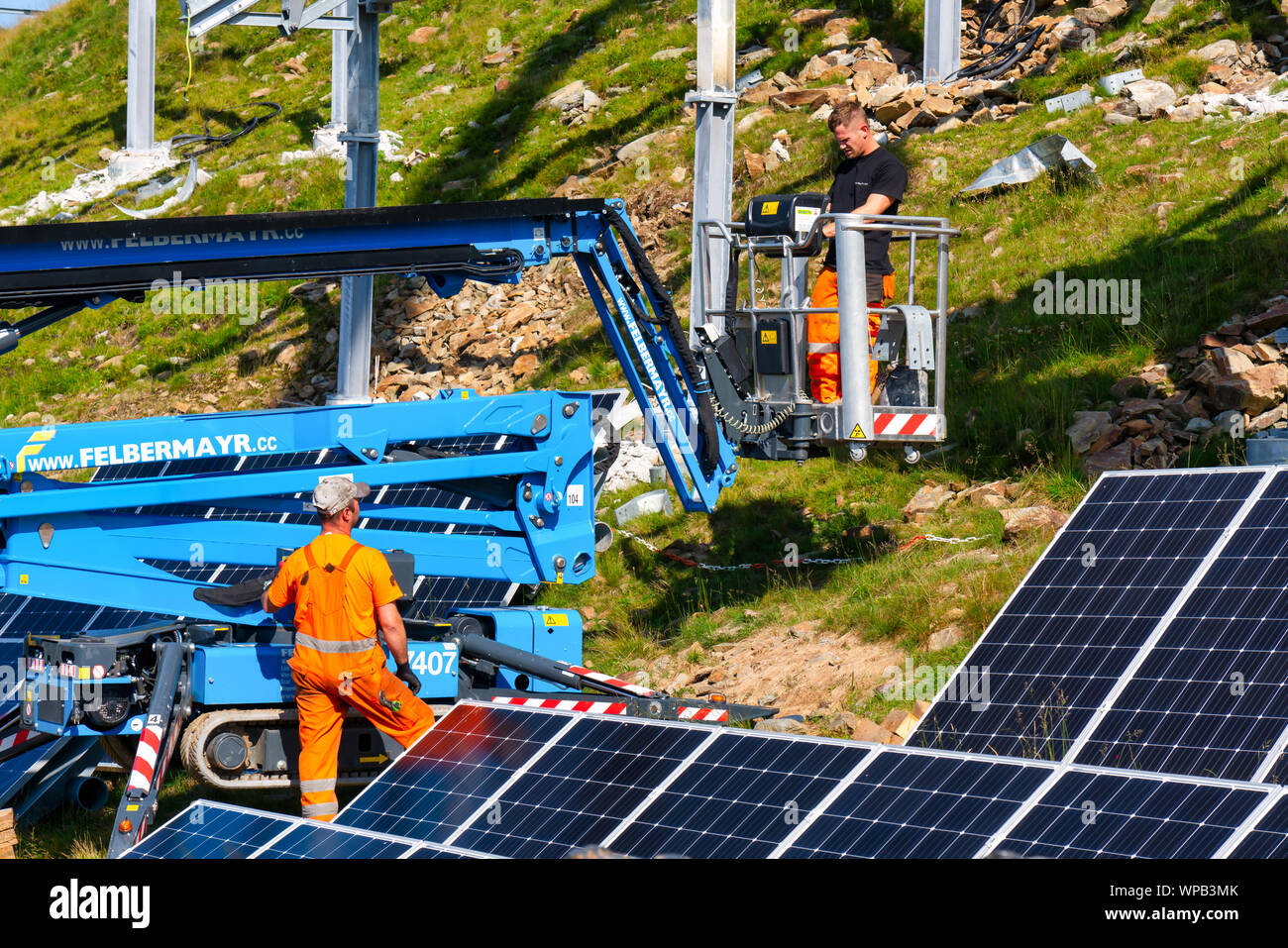 Neukirchen, Austria, 08/29/2019: Workers preparing the lifting a solar cell to the mounting system solar construction. Green energy. Stock Photo