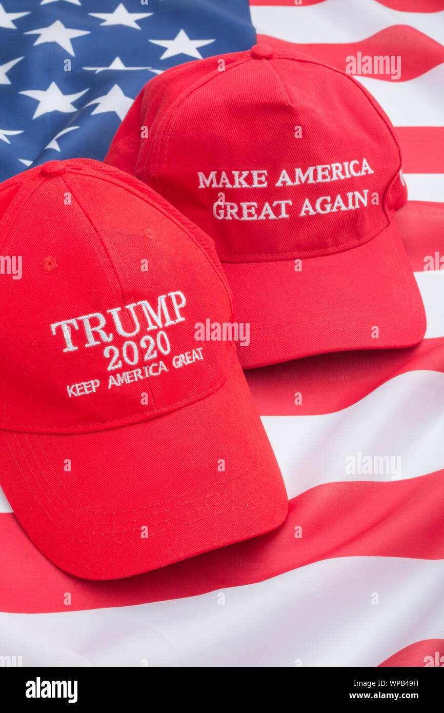 Red Trump MAGA & Keep America Great hats + U.S Stars & Stripes flag. Metaphor Trump supporters, Trump presidency, 2020 US elections, Trump America 1st Stock Photo