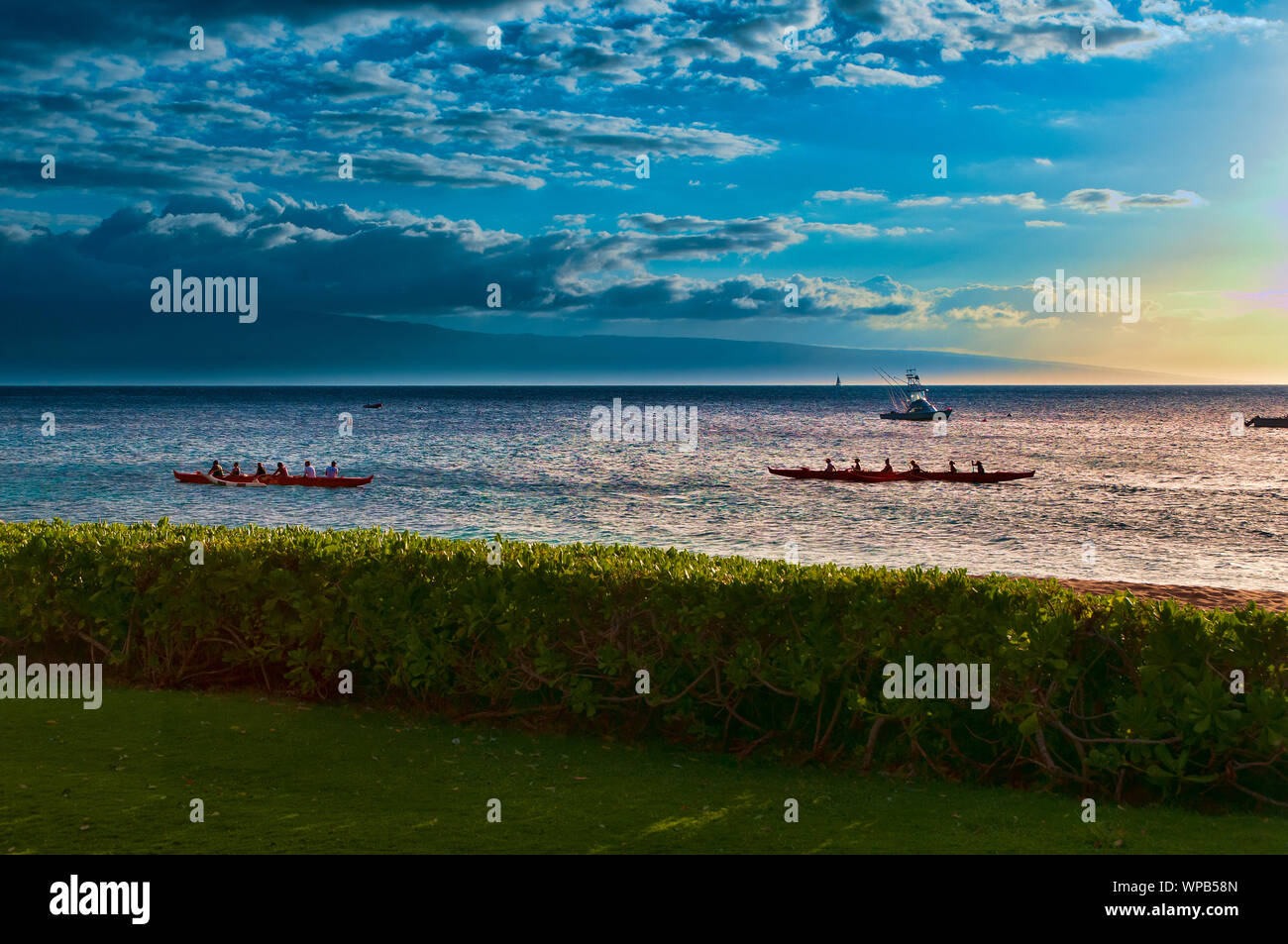 Two native Hawaiian boats rowing past at sunset on Maui, Hawaii, USA