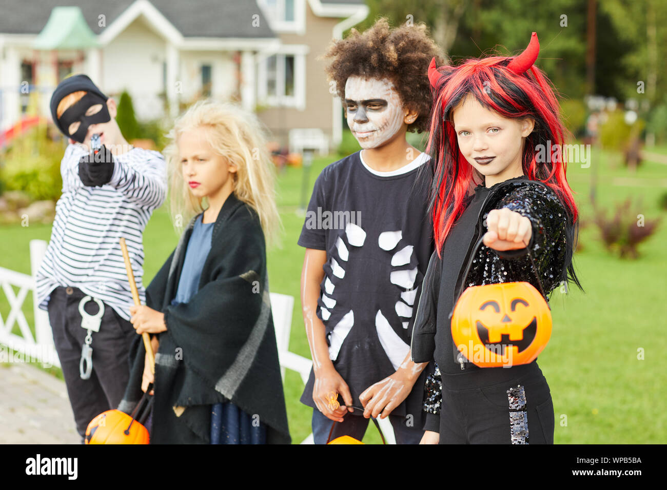 Group of children trick or treating on Halloween, all wearing costumes while posing outdoors Stock Photo