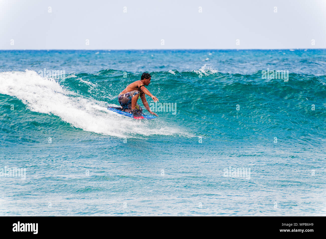 KOLOA, KAUAI, HI - APRIL 24, 2008 - Young man riding a boogie board in a blue wave in the summer. Stock Photo