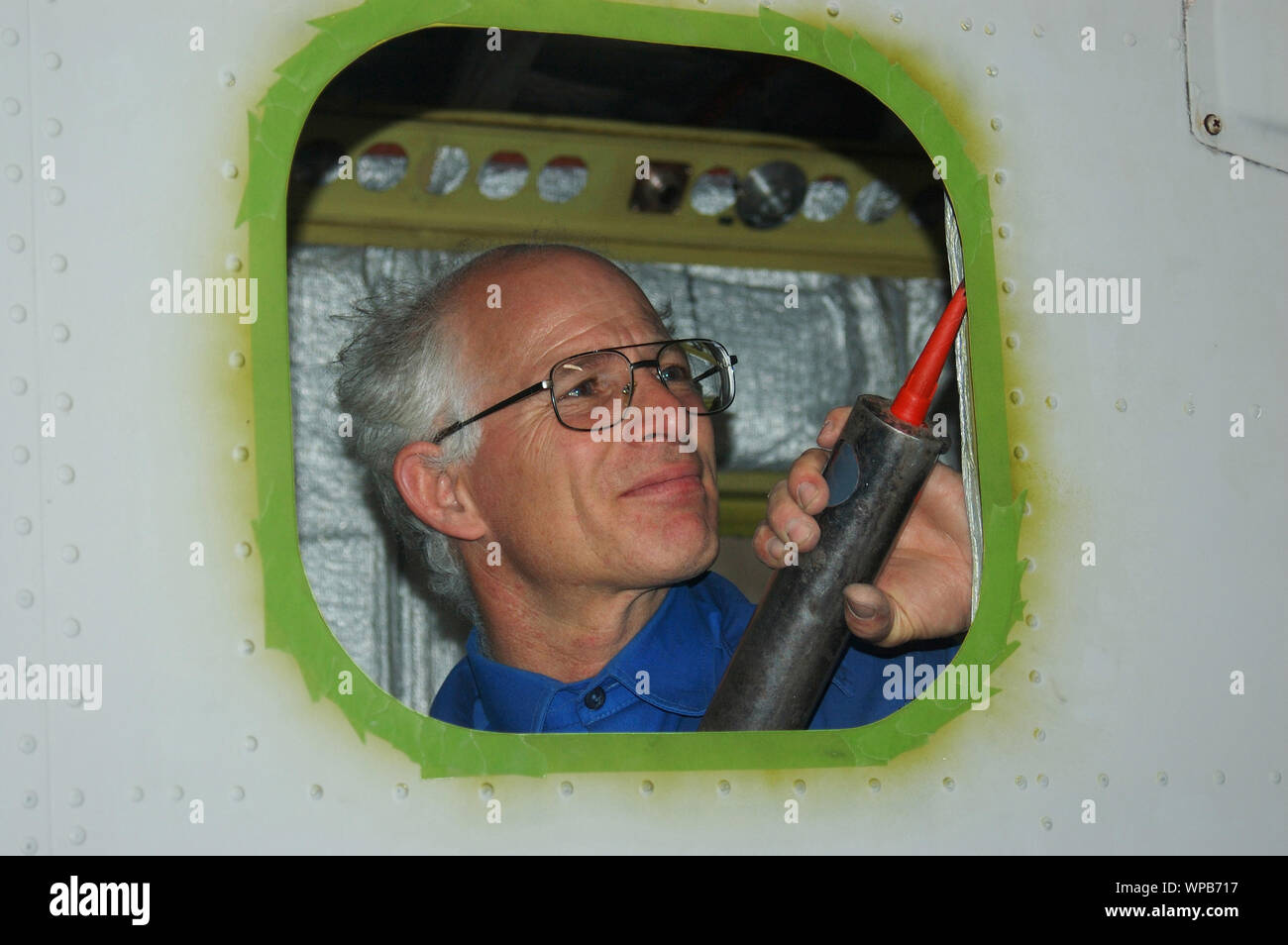 A tradesman placing sealant for the installation of perspex aircraft windows in a Dornier 228 Stock Photo