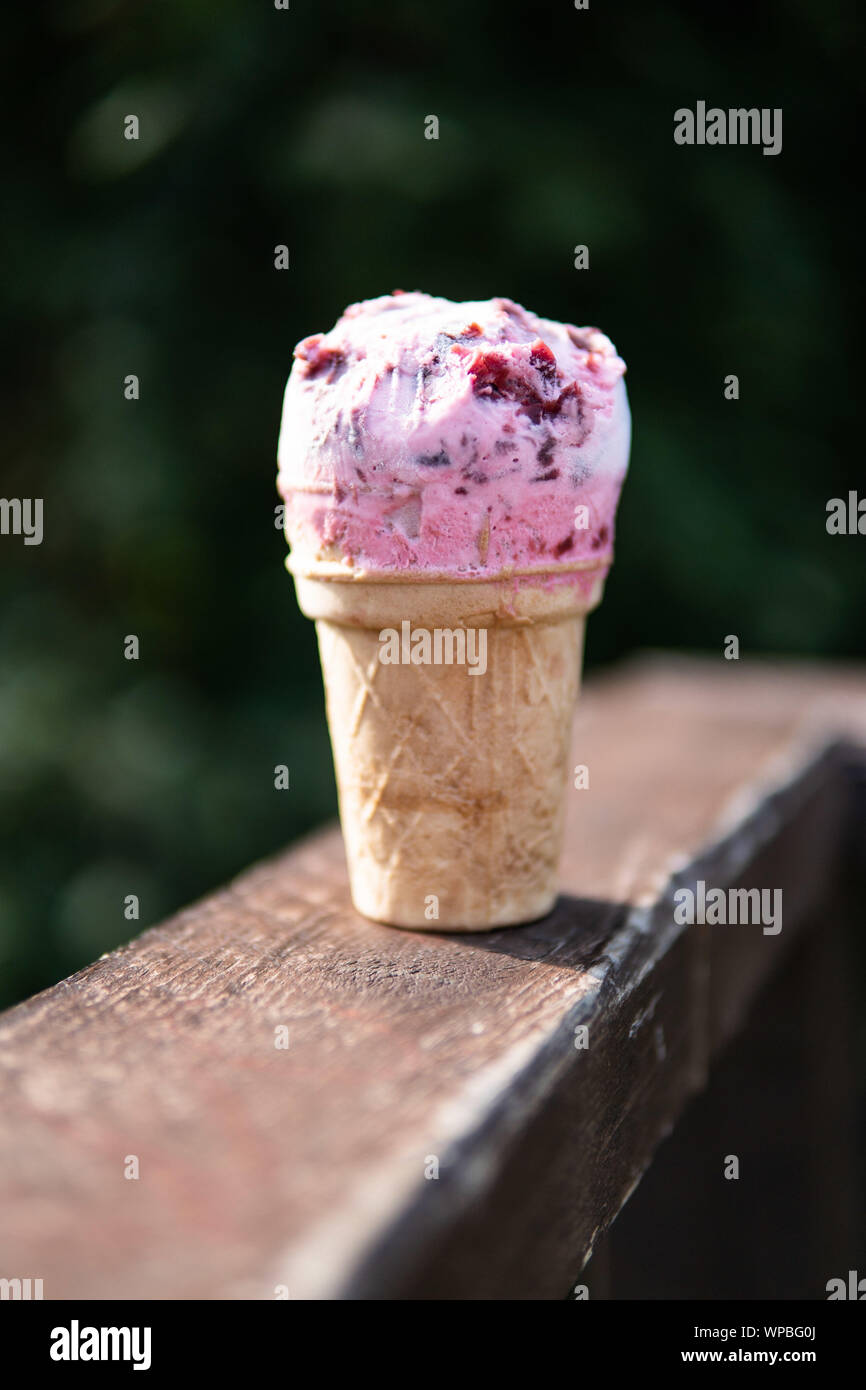 Waffle ice cream with cherry filling on a wooden table on a green