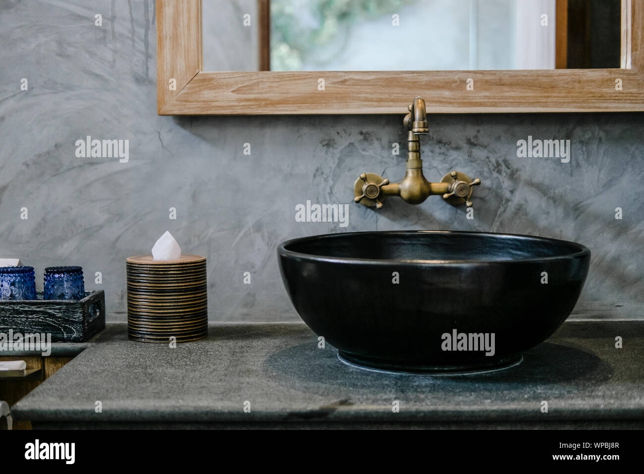 Black sink, vintage copper faucet, gray wall, mirror, loft bathroom interior details. Close up, minimalism concept Stock Photo