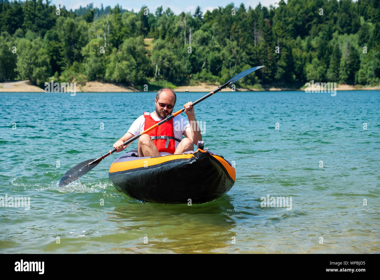 Man paddling in inflatable kayak on lake Lokve, in Gorski kotar, Croatia. Adventurous kayaking experience in a beautiful nature. Stock Photo