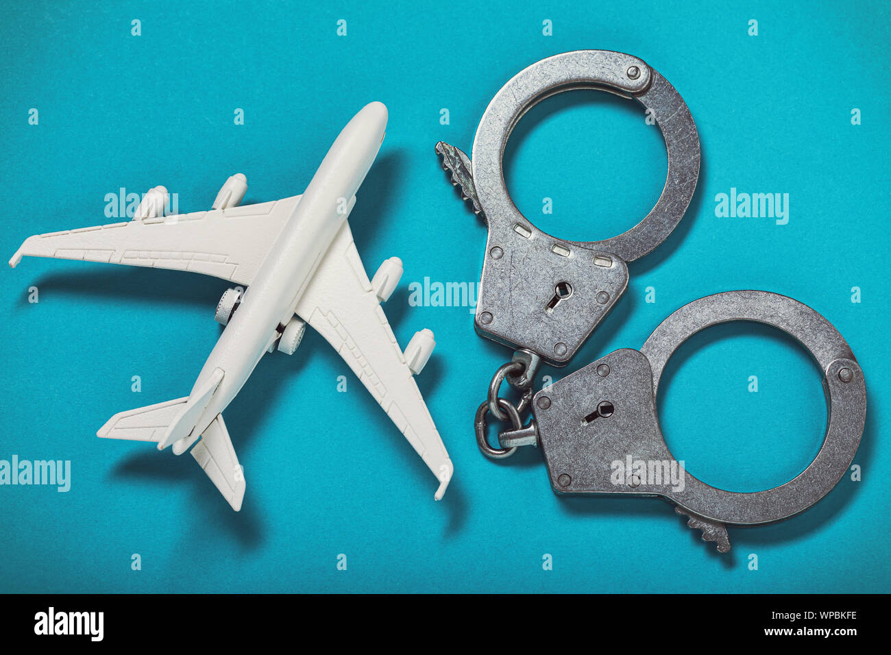 Airplane and handcuffs on the table, top view. Concept on the topic of