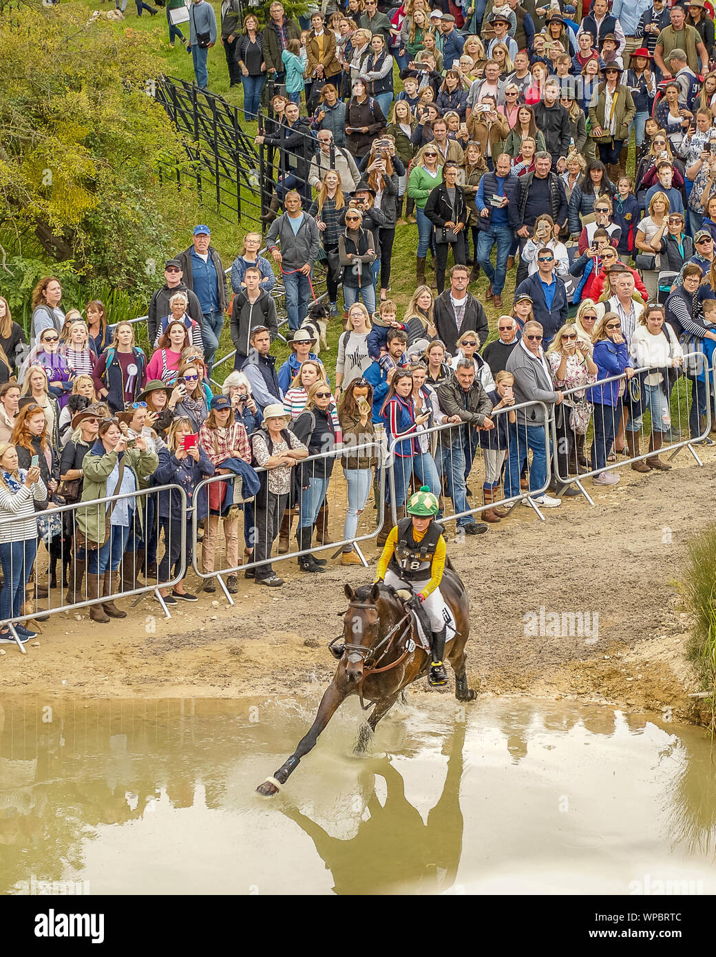 Cross country horse and rider gallop down the hill and into the water at the Burghley Horse Trials Stock Photo