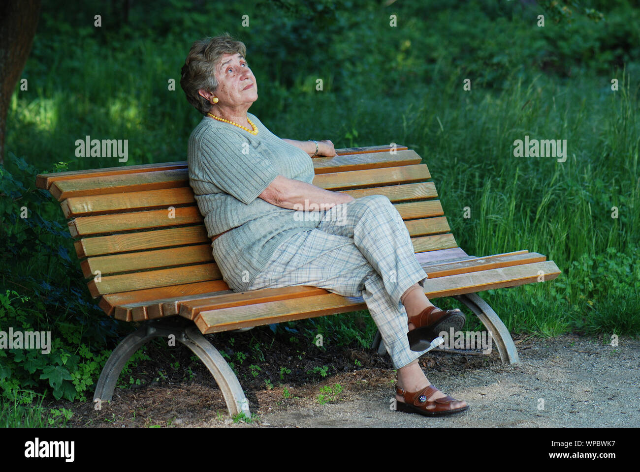 elderly woman sitting on park bench Stock Photo