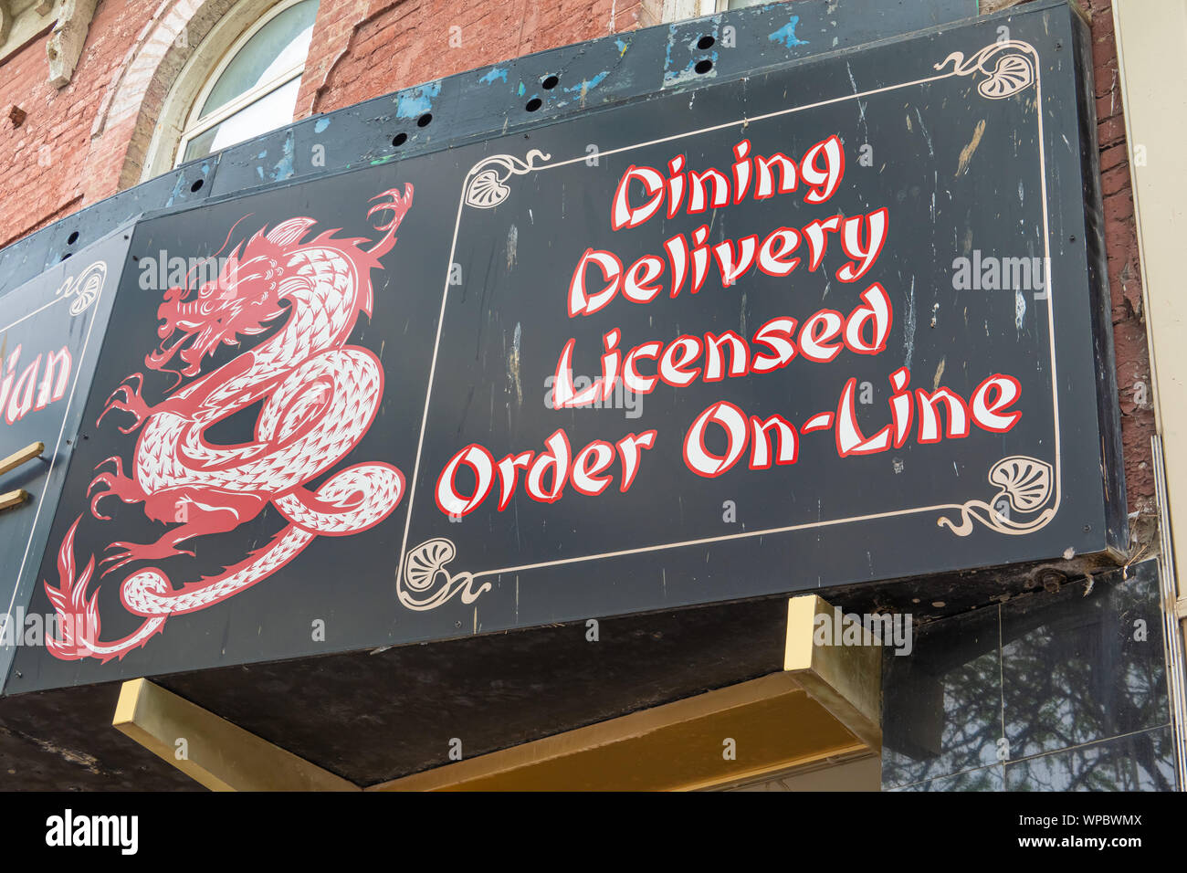 A weathered sign covered in bird droppings sits atop an out of business chinese restaurant. Stock Photo