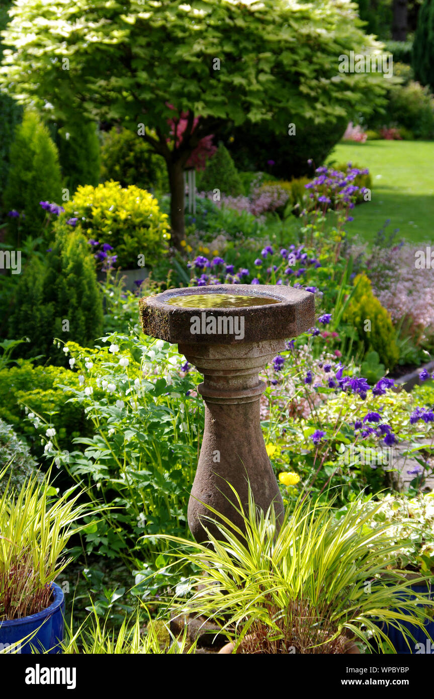 English country garden with stone bird bath Stock Photo