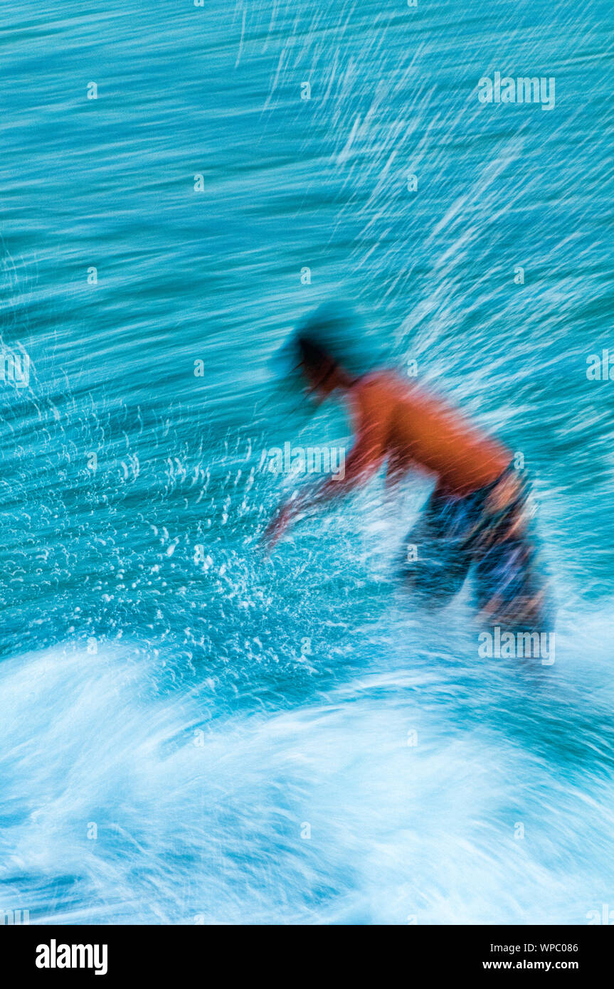 Teenage boy skimboarding on the tropical island of Kauai, Hawaii, USA