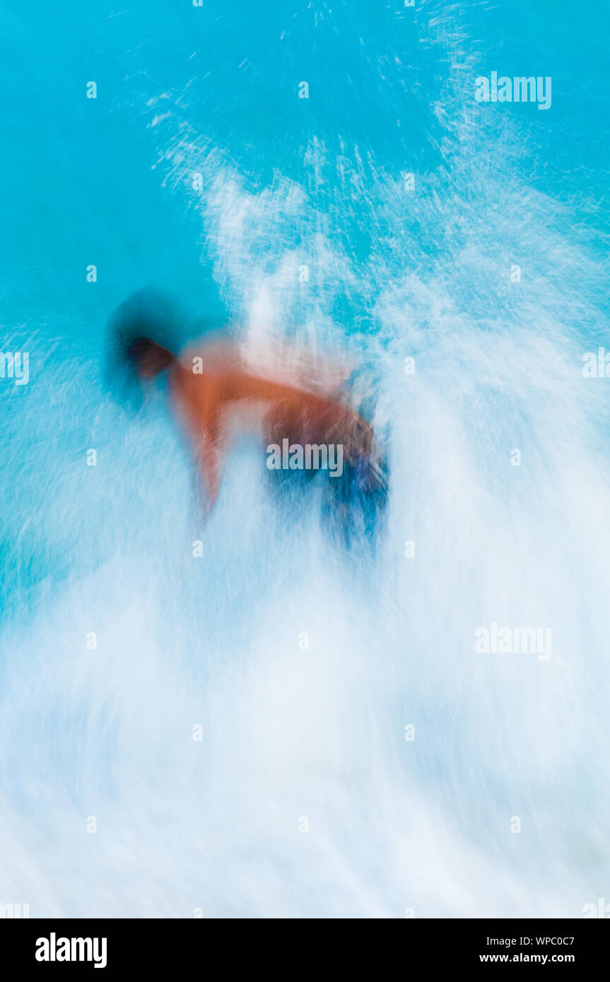 Teenage boy skimboarding on the tropical island of Kauai, Hawaii, USA