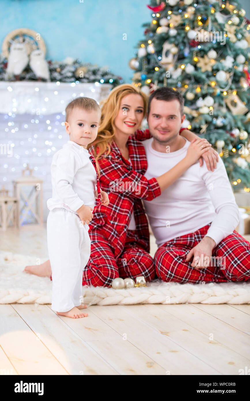 Happy smiling family in checkered pajamas near the Christmas tree and New Year s fireplace Stock Photo Alamy