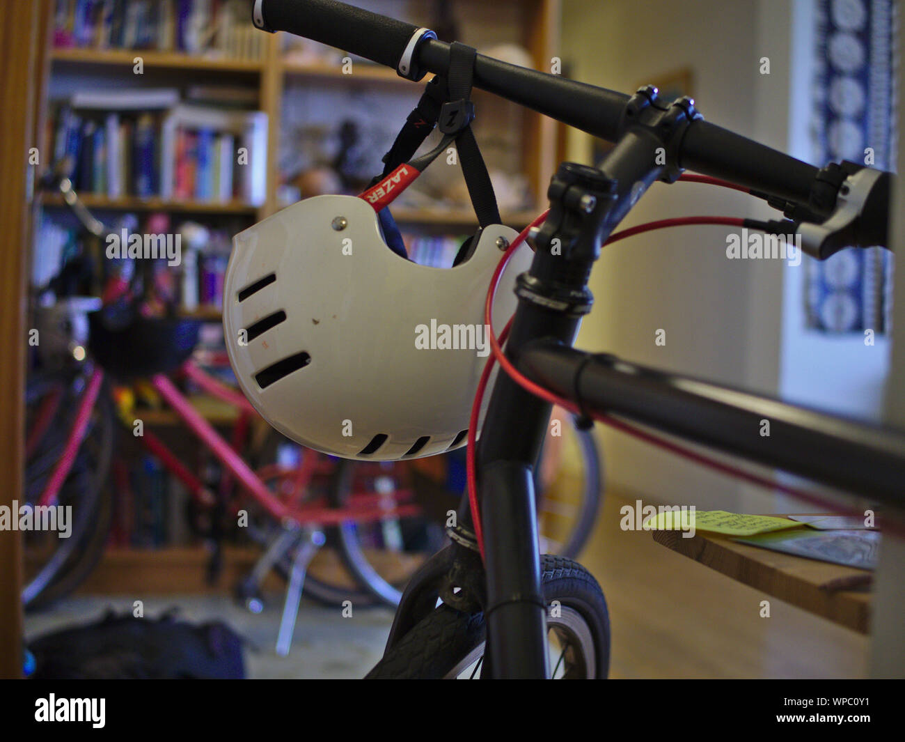 White bicycle helmet (bmx style) hanging from the handlebars of a black  homemade fixie bicycle inside an apartment Stock Photo - Alamy