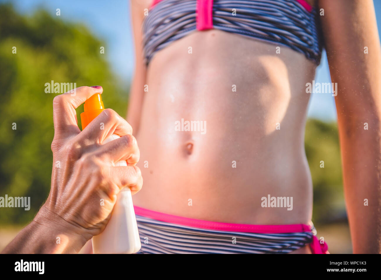 Mother applying sun protection cream to her daughter on the beach Stock Photo