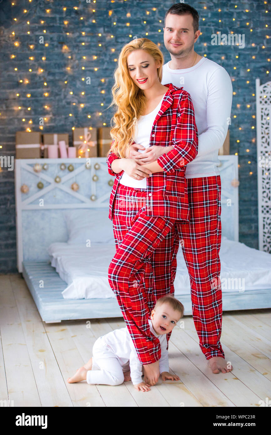 Loving happy couple husband and wife in plaid pajamas stand near
