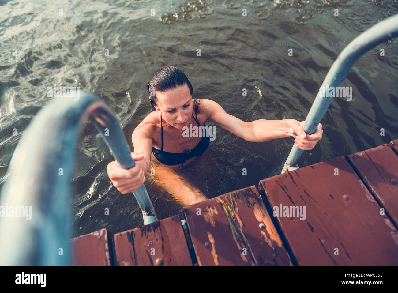 Women getting out of water using ladder Stock Photo