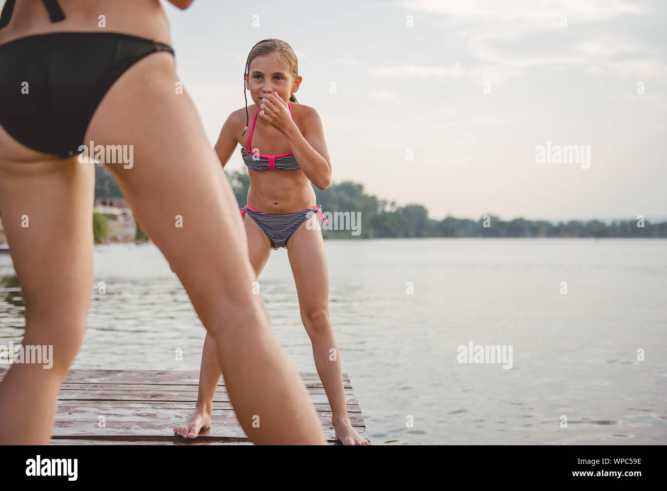 Girl playing with her mother on the dock by the river Stock Photo