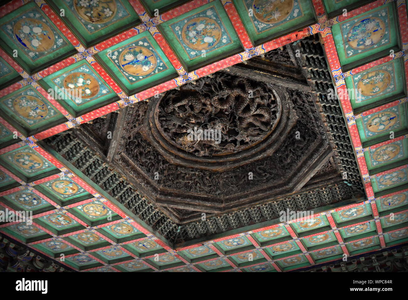 Old Chinese wooden dragon and beautifully colored ceiling of Fubi pavilion of the Forbidden City palace imperial garden, Beijing, China Stock Photo