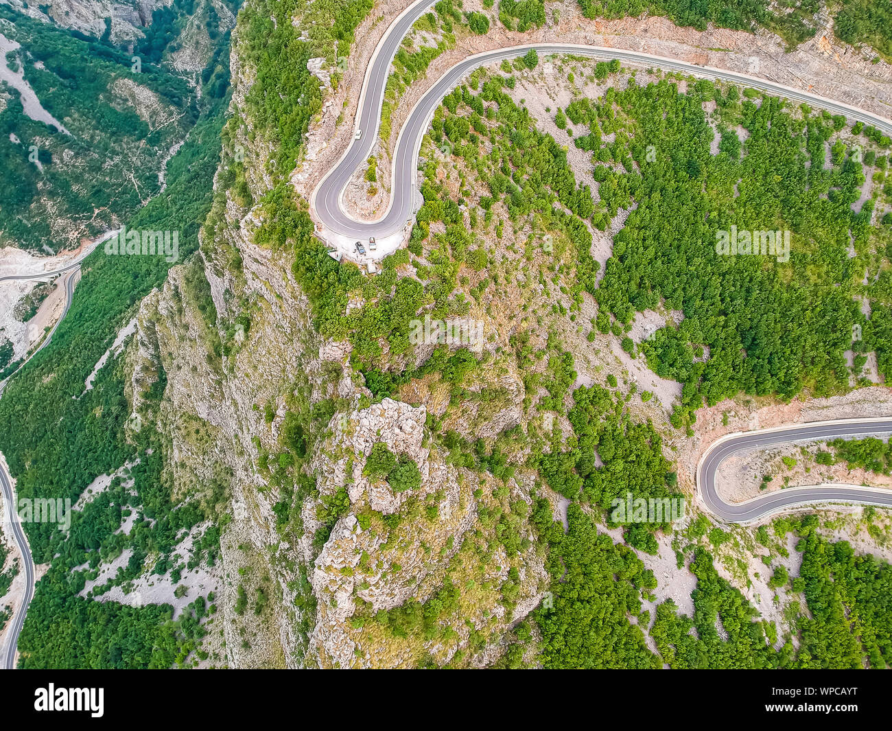 Off road cars on cliff by serpentine road in Albanian mountains near