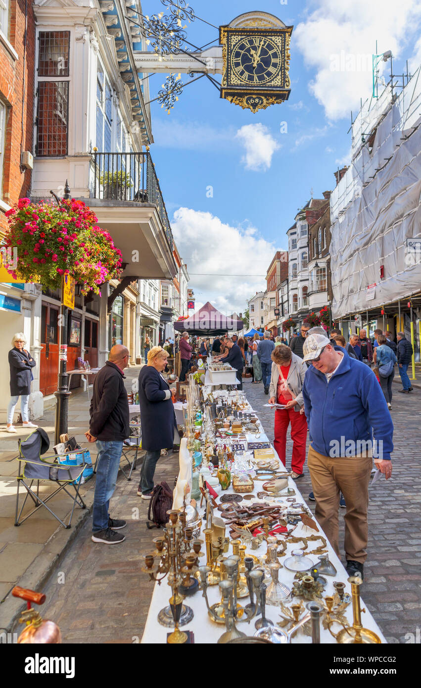 Stall and view of stalls in the Guildford Antique & Brocante Street Market under historic clock