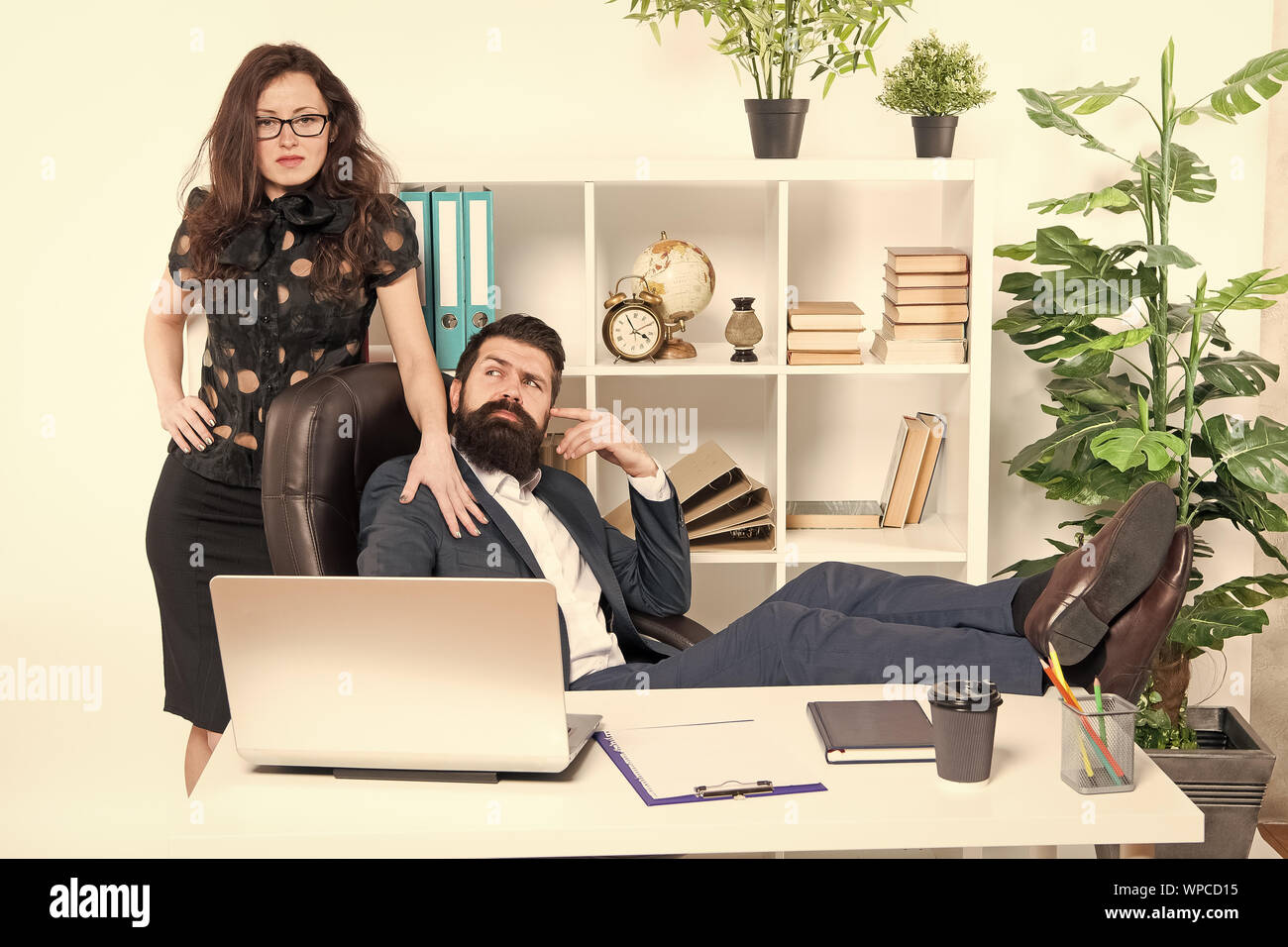 Lazy boss office. Offer massage. Man bearded hipster boss sit in leather armchair office interior. Boss and secretary girl at workplace. Relations at work. Business people and staff concept. Stock Photo