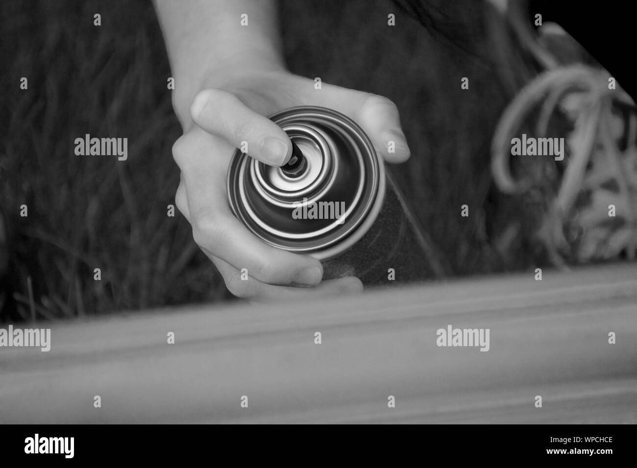 Hand holding a spray can preparing to paint a frame. Black and white