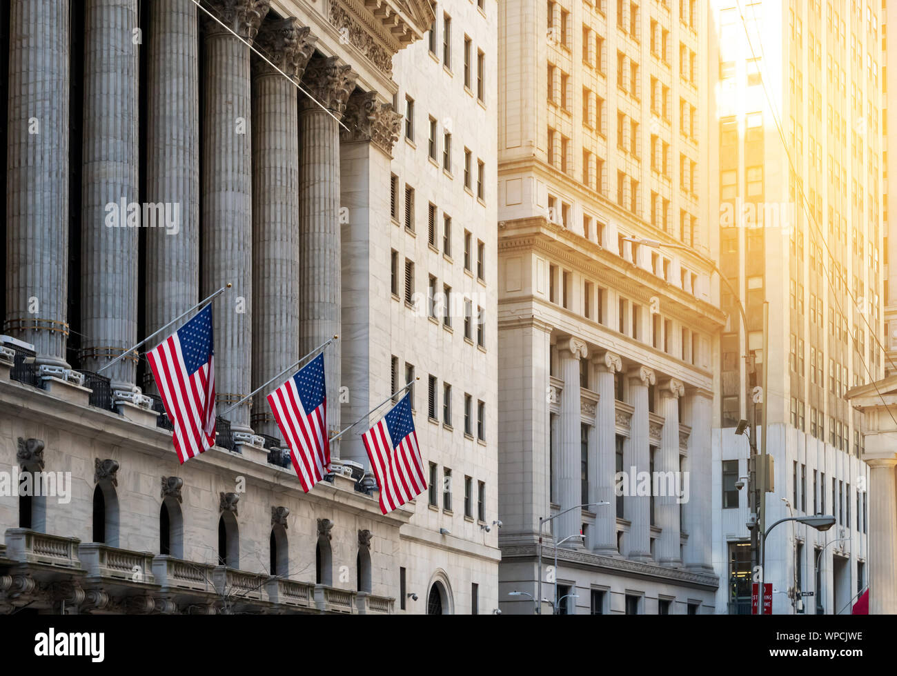 American flags flying in front of the historic buildings of Wall Street