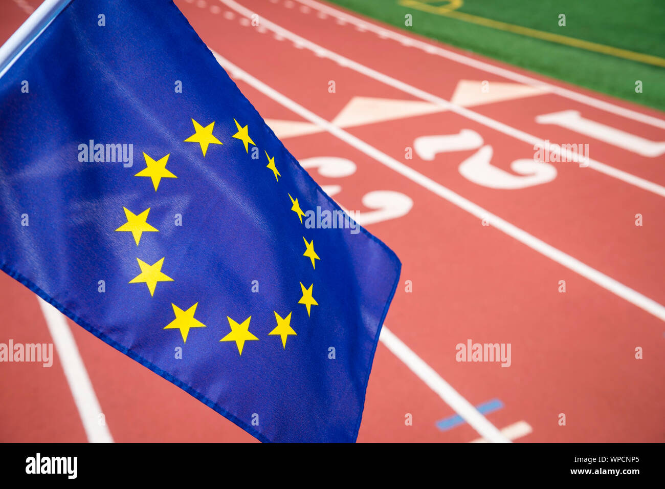 European Union flag flying in front of a red athletic track background with copy space for post-Brexit competition Stock Photo