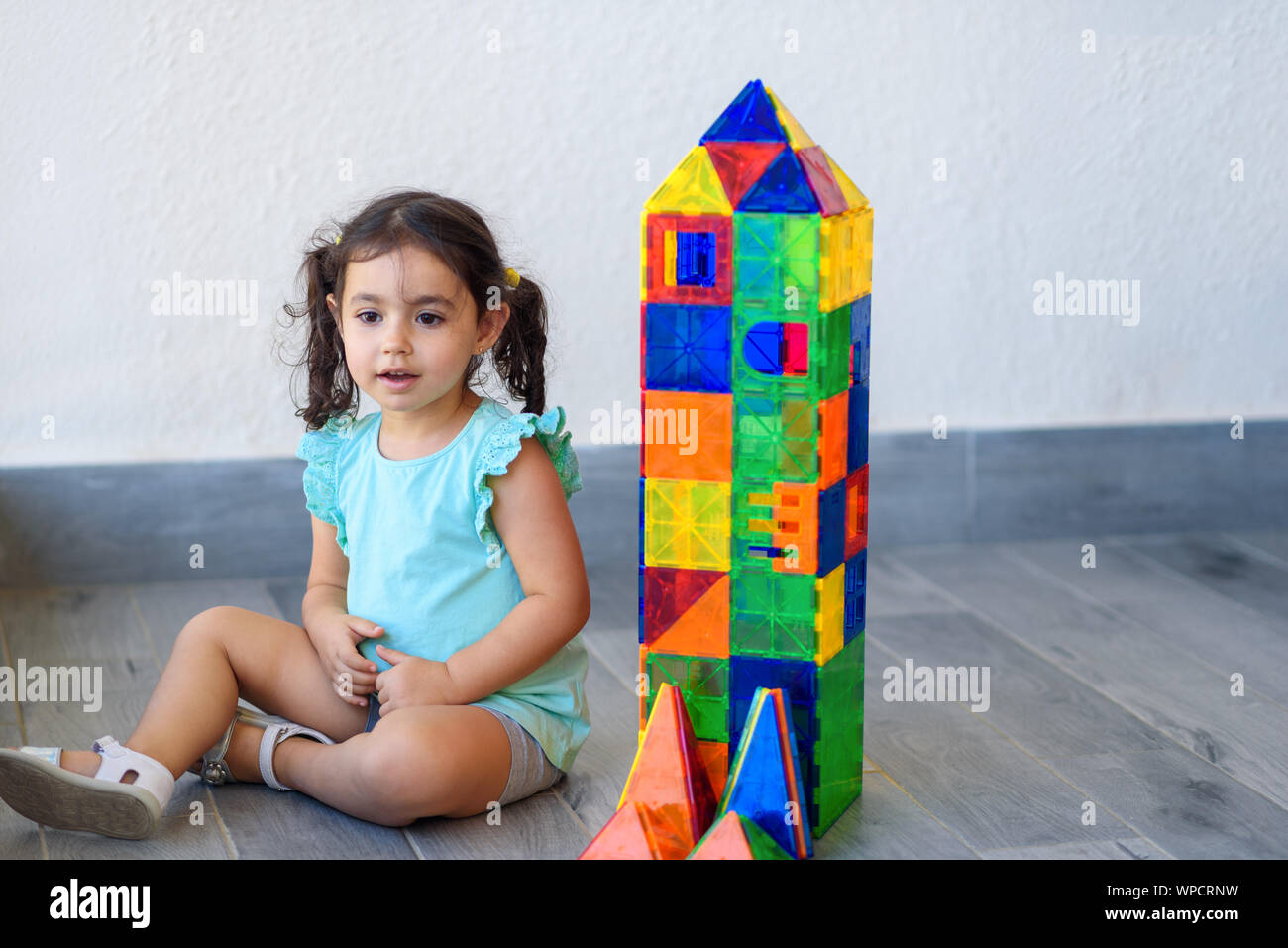 Little girl playing with lots of colorful plastic blocks constructor ...