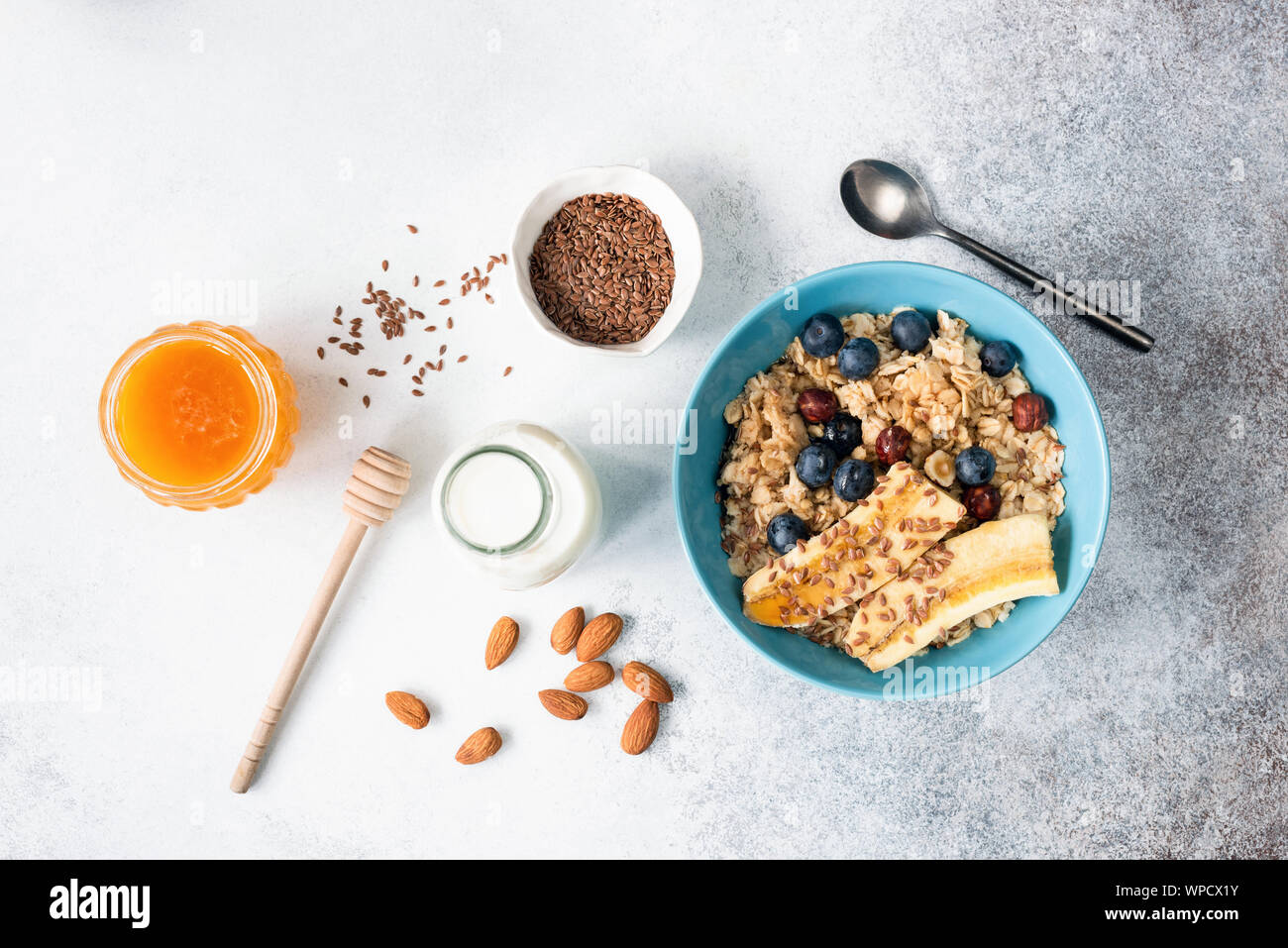 Oatmeal or breakfast oats porridge with fruits, flax seeds, honey in a bowl. Table top view. Healthy breakfast food ingredients, clean eating concept Stock Photo