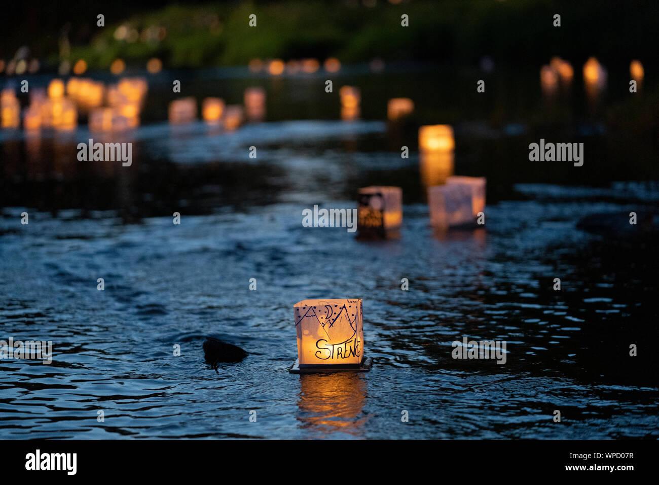 Many water Lanterns float downstream from people releasing them at Pamperin Park in Green Bay, Wisconsin Stock Photo