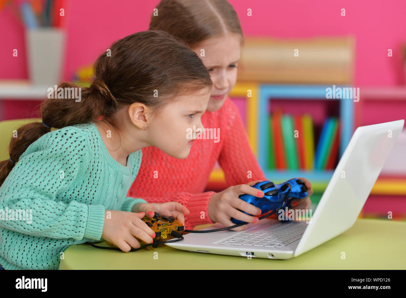 Two excited girls playing game on laptop Stock Photo - Alamy