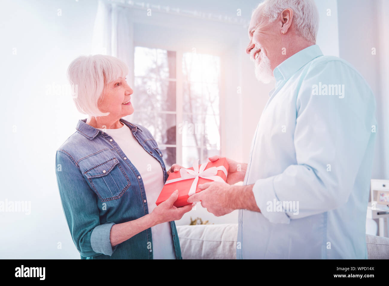 Caring loving mature husband making little surprise for his beautiful woman Stock Photo