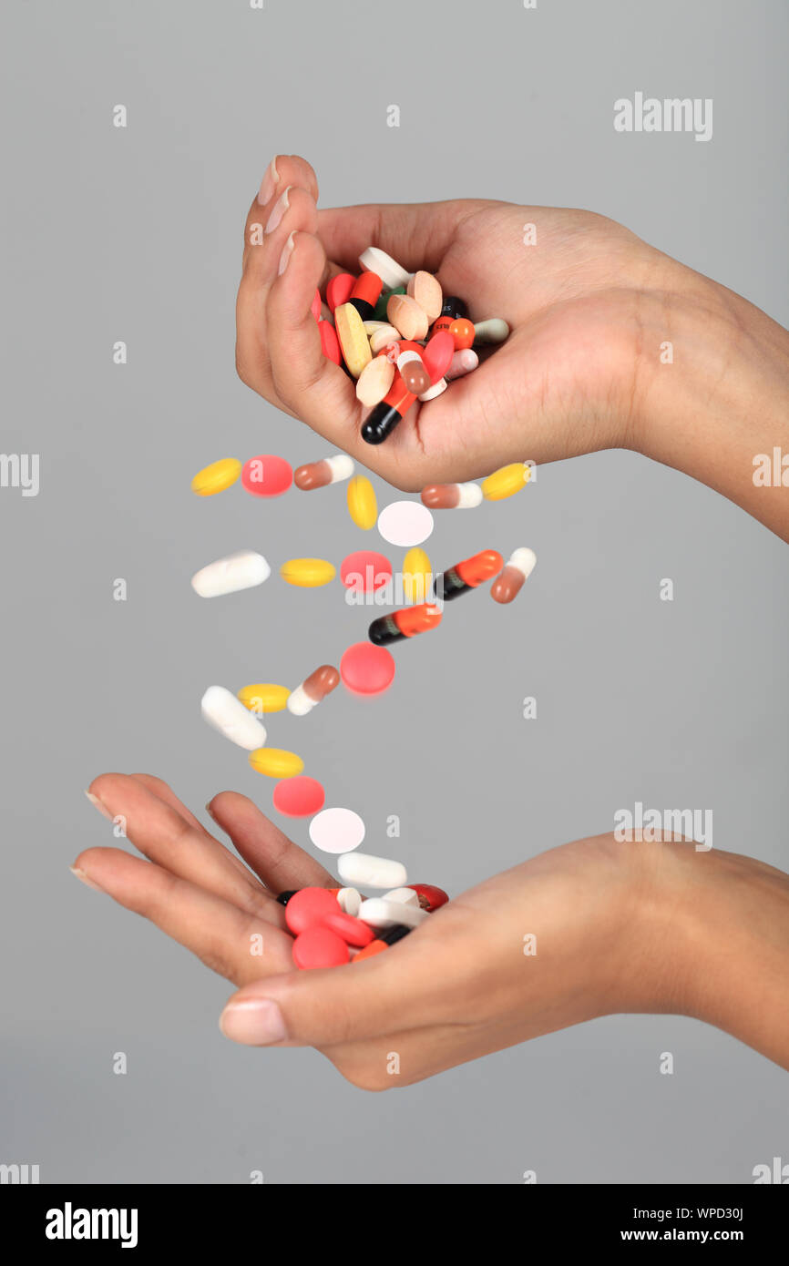 Close-up of a person's hand pouring pills on another hand Stock Photo