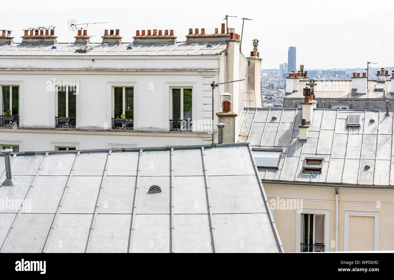 Metal roofs of residential multi-storey apartment houses with small metal balcony outside of the windows and clay roof chimneys located on one of the Stock Photo