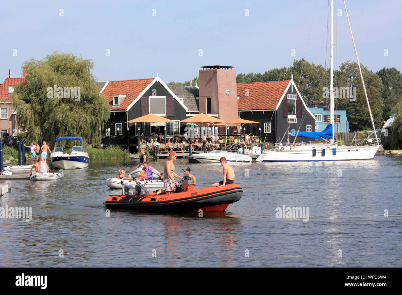 People enjoying outdoor dining in Volendam on a warm sunny day in summer while the others are doing sports boating. Stock Photo