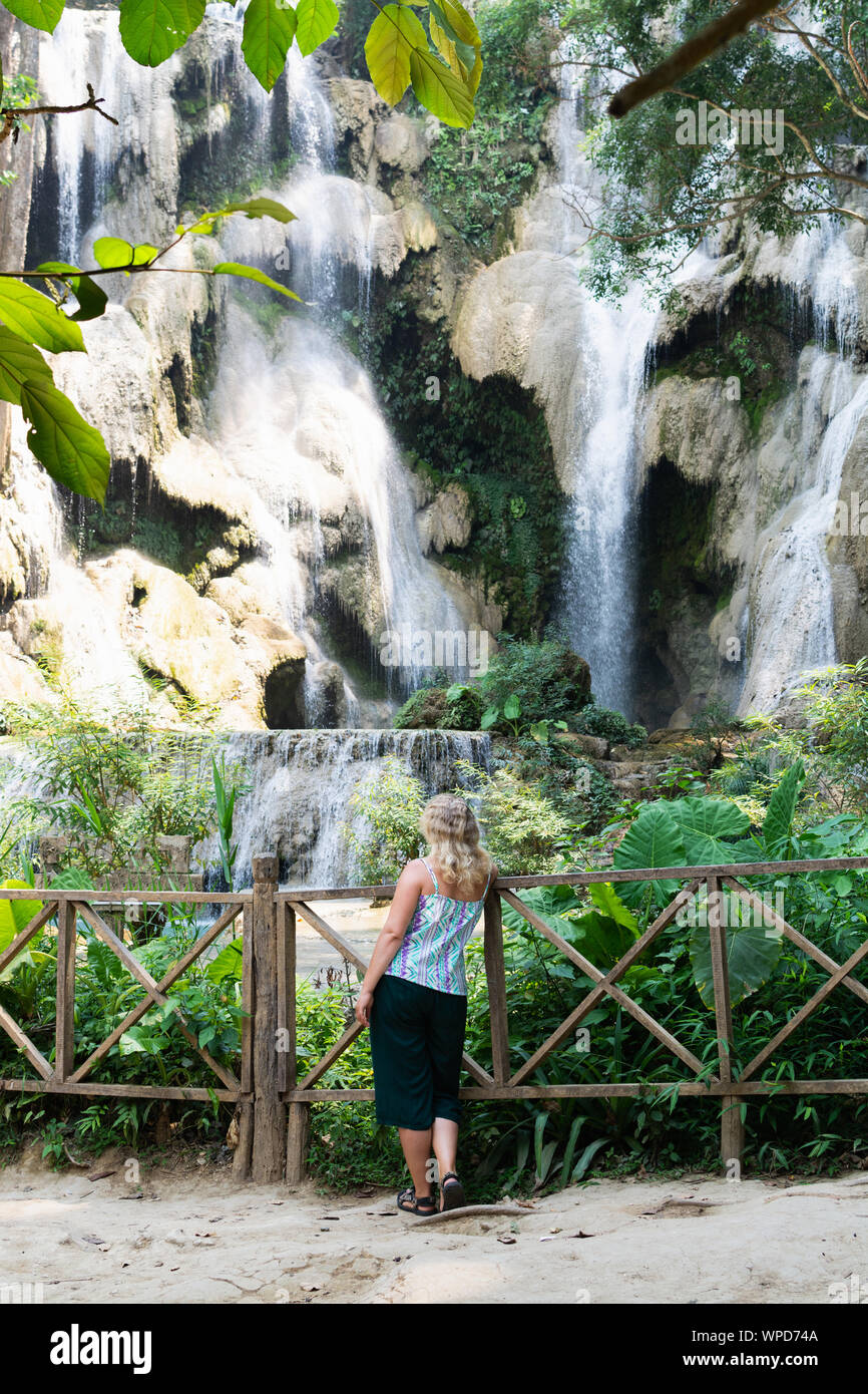Blonde Caucasian woman standing in front of Kuang Si waterfall close to ...