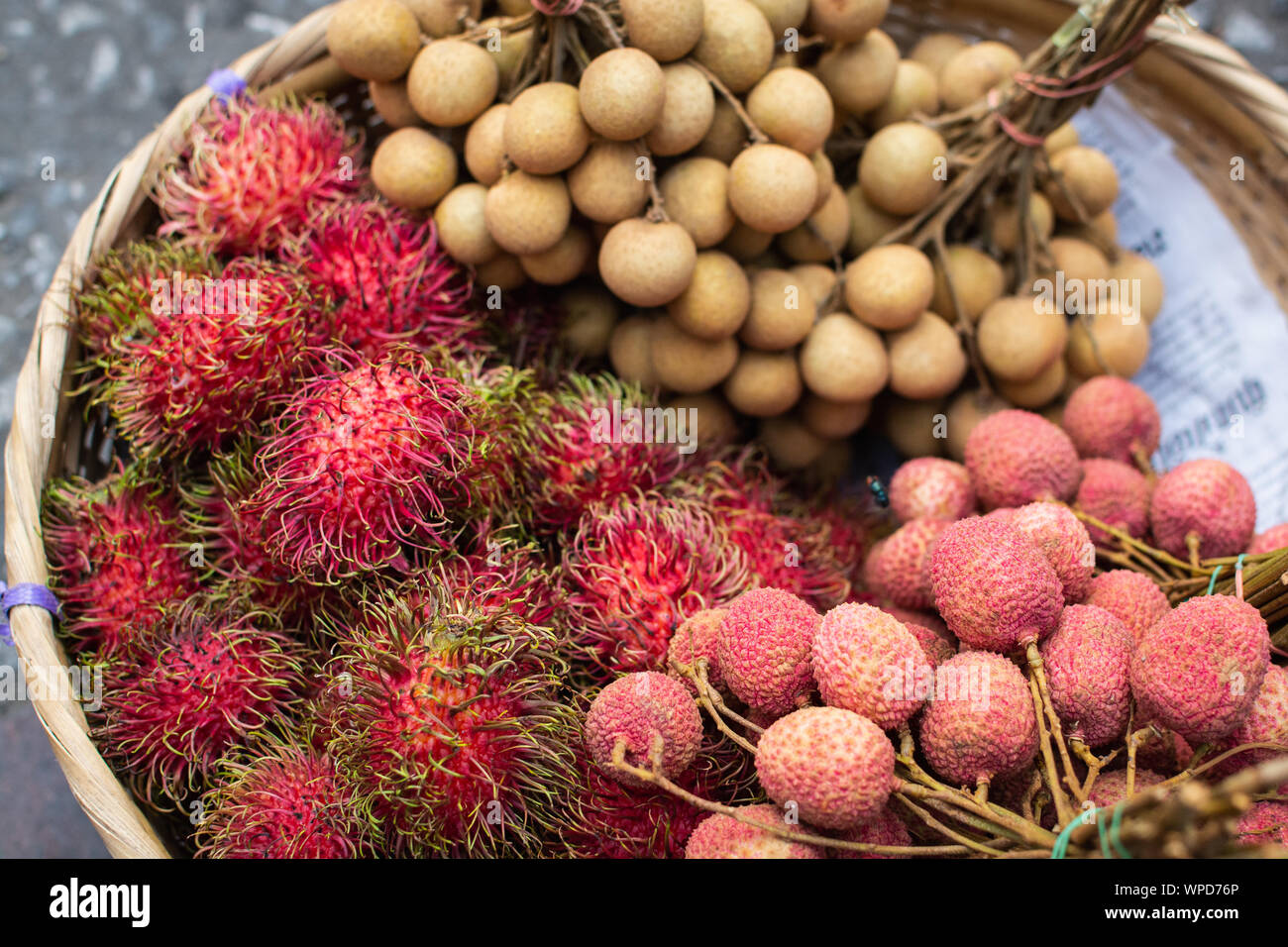 Basket with fresh exotic fruits of rambutan, lychee and longan on Asian market Stock Photo