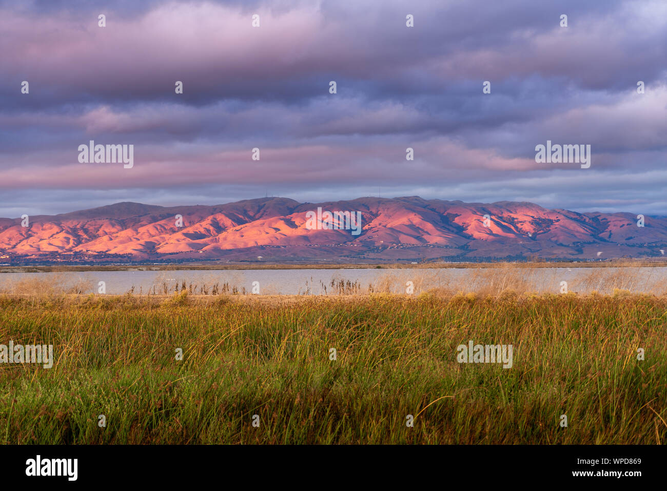 Sunset landscape in South San Francisco bay, colorful clouds covering the sky; mountains slopes and peaks (part of the Diablo mountain range) colored Stock Photo