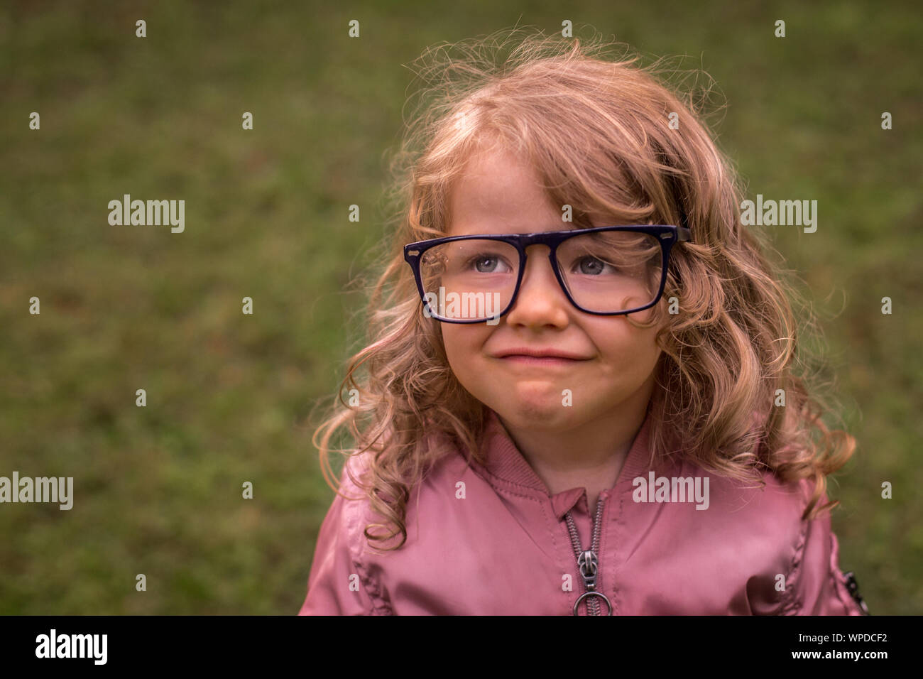 Little, beautiful adorable preschooler girl smiling, with adult eye glasses, too big for her size, room for your text Stock Photo