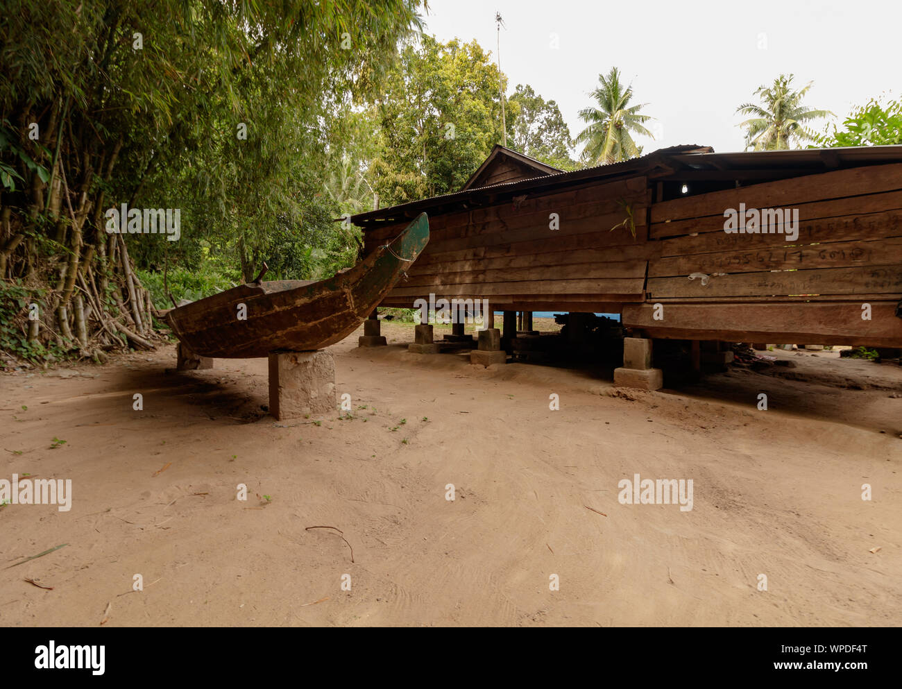 A wooden boat next to a wooden house in Asia. Stock Photo