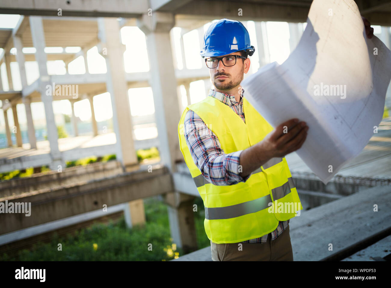 Engineer working on construction site and holding blueprint Stock Photo ...
