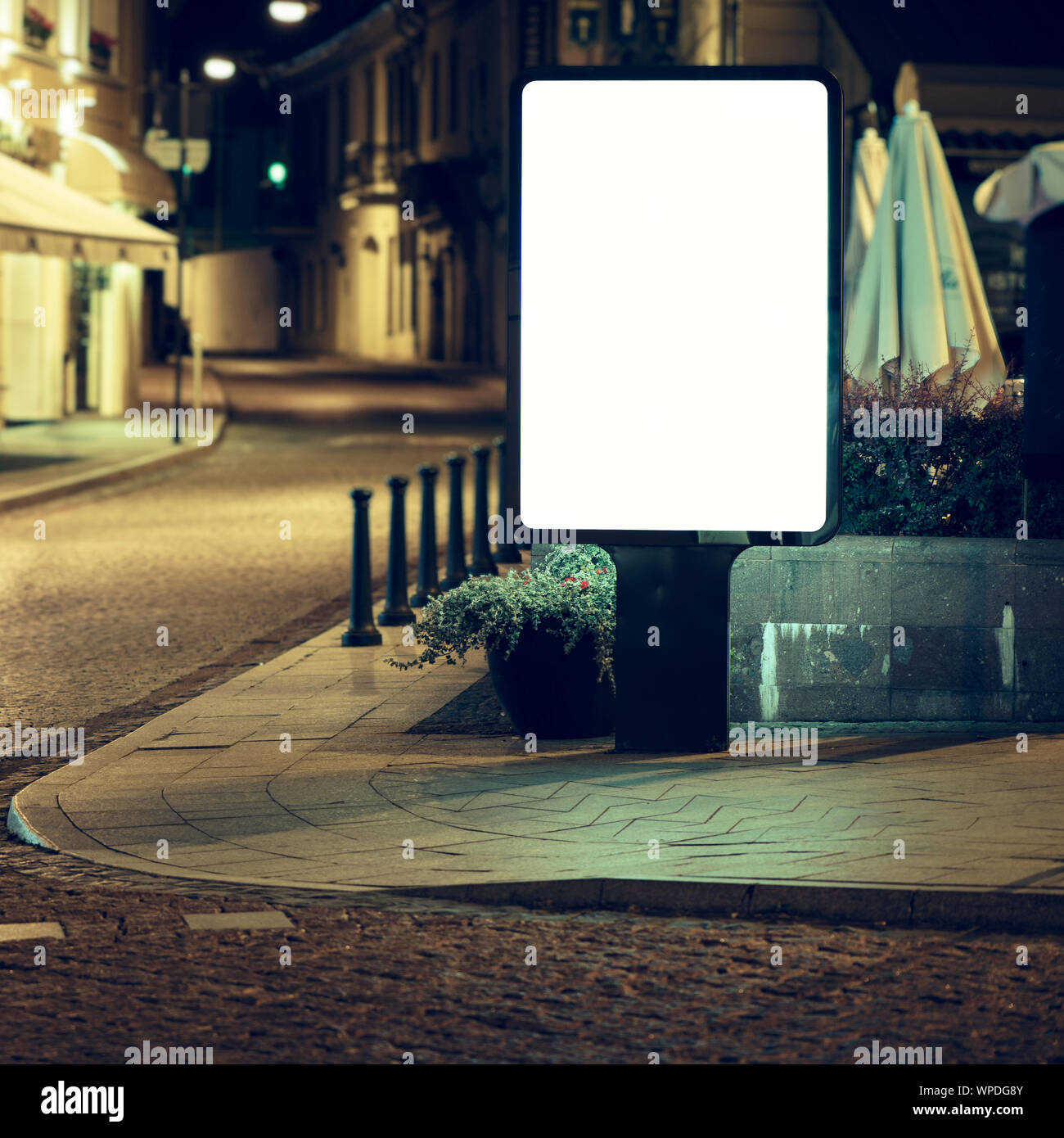 Blank advertising billboard in old town at night. Stock Photo