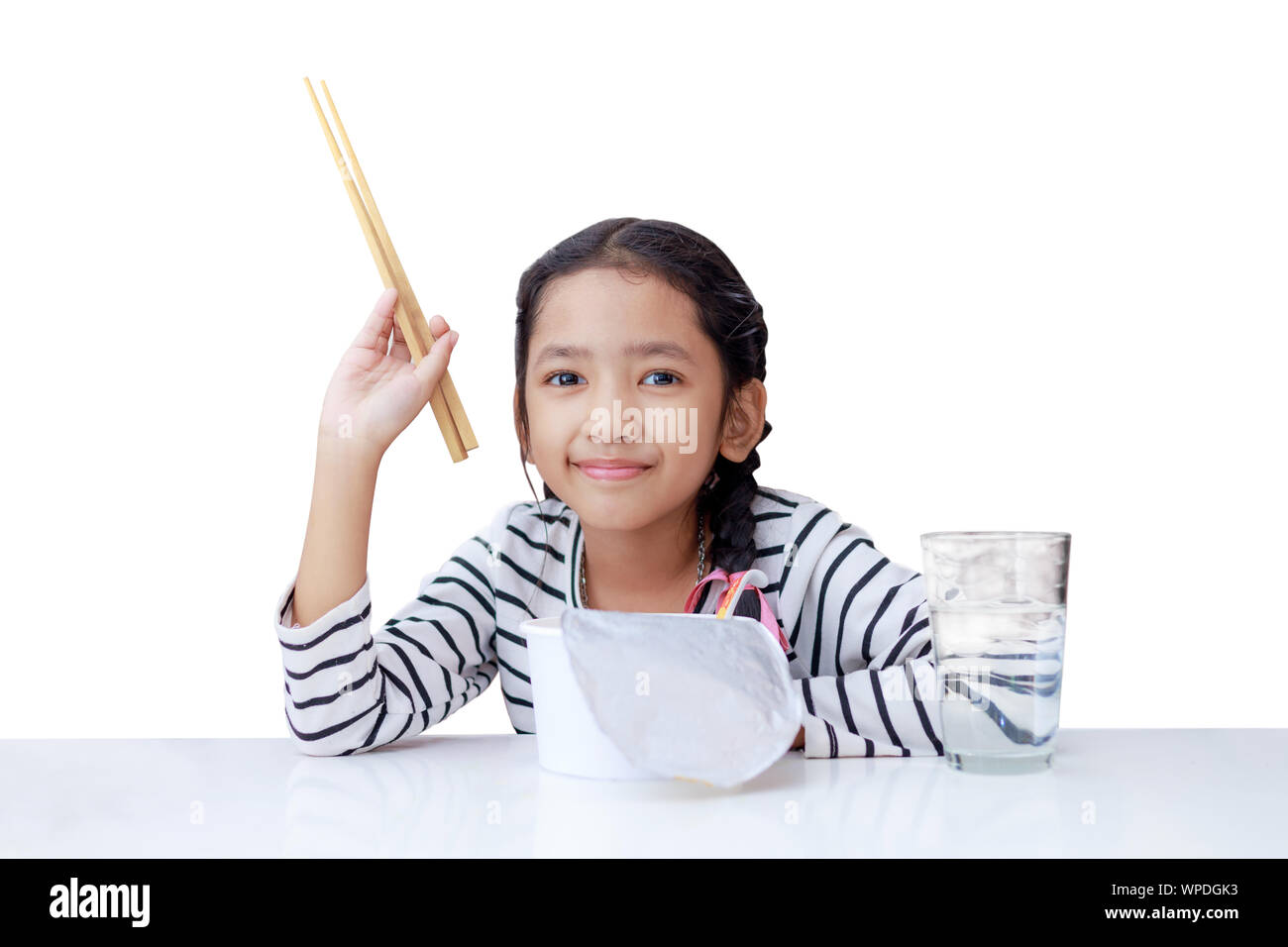 Little Asian girl eat instant noodle and smile with happiness on the white background select focus shallow depth of field Stock Photo