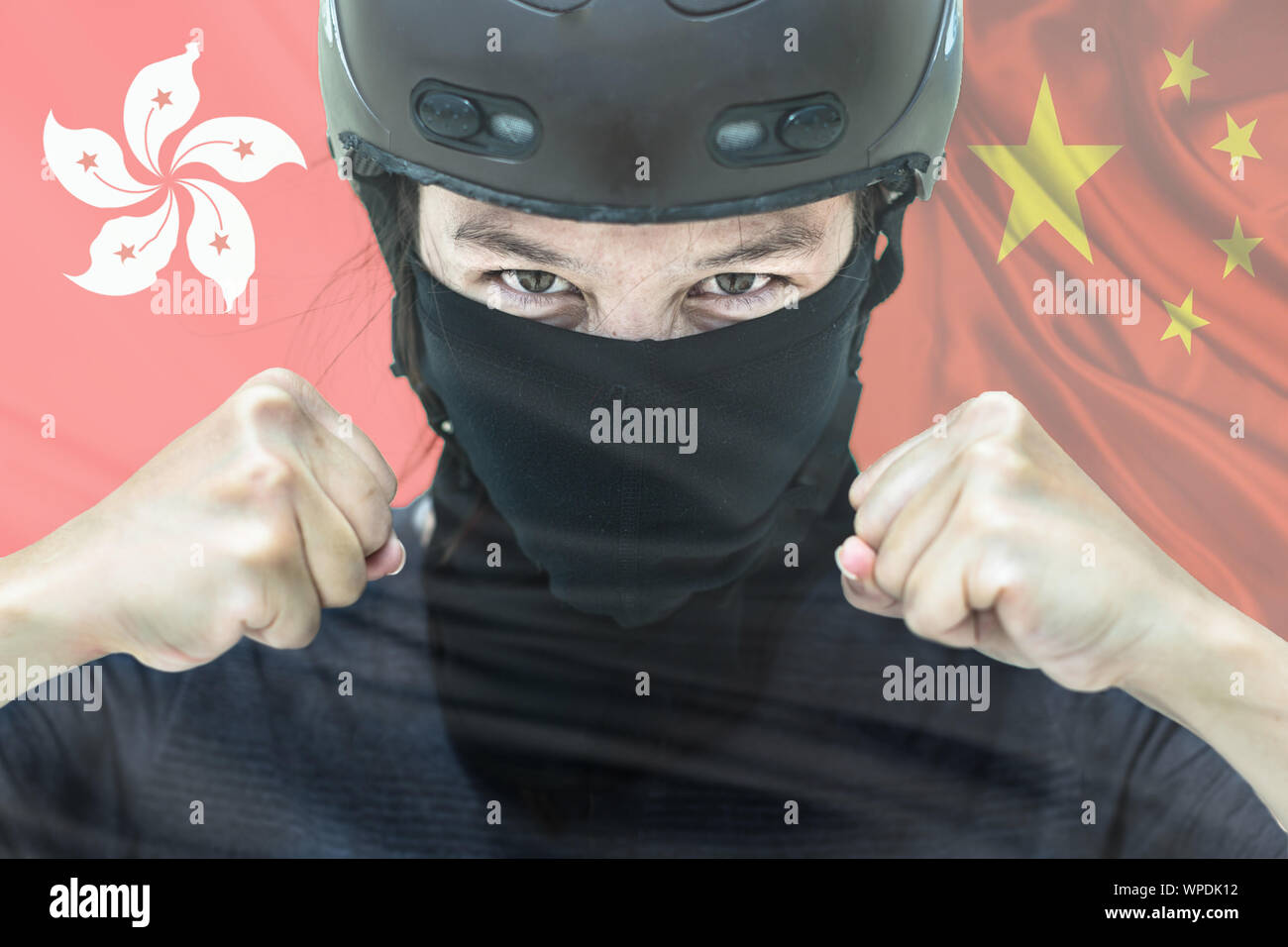 A portrait of a protestor in riot gear with the hong kong and chinese flags in the background Stock Photo