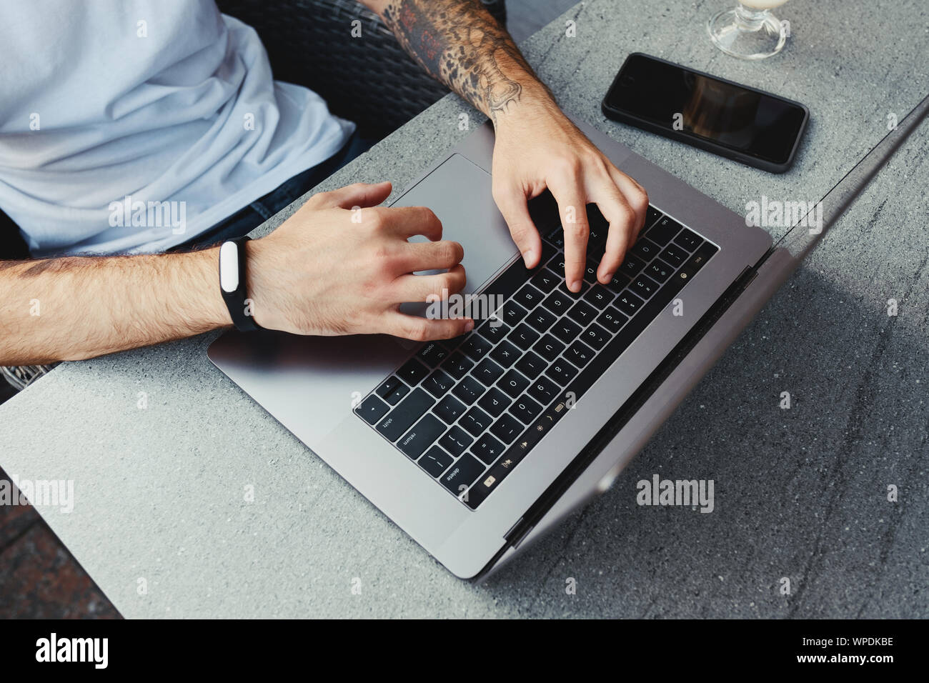 Top view male hands using notebook outdoors in coffee shop while typing on keyboard, businessman freelancer working on portable computer, browse inter Stock Photo