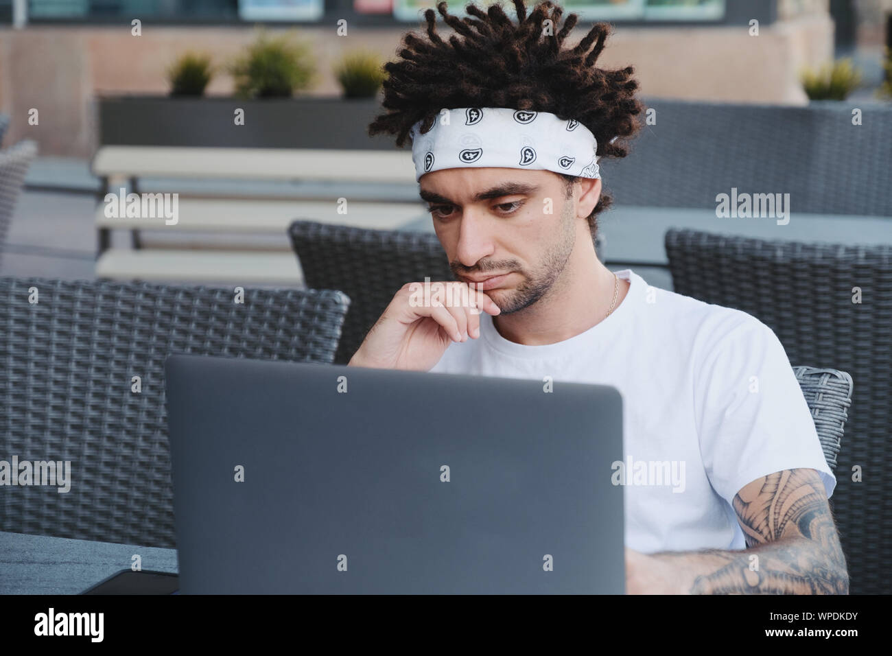Thoughtful freelancer it developer thinking about fixing software bugs on laptop. Focused student watching tutorial on e-learning website platform, le Stock Photo